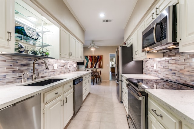 kitchen with sink, tasteful backsplash, ceiling fan, light stone countertops, and appliances with stainless steel finishes