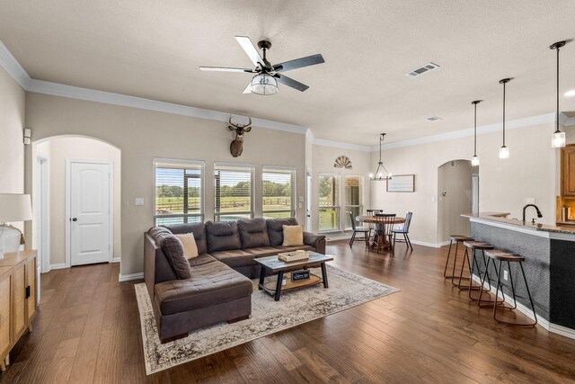 living room with dark hardwood / wood-style floors, a textured ceiling, crown molding, and ceiling fan