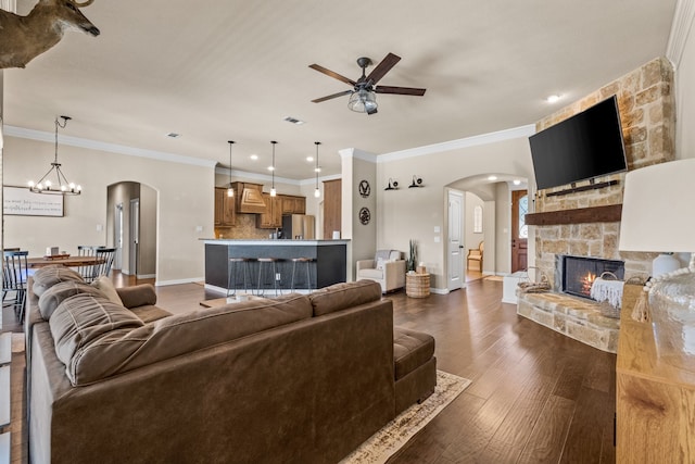 living room featuring a fireplace, dark hardwood / wood-style floors, ceiling fan with notable chandelier, and ornamental molding