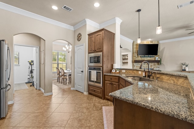 kitchen with light tile patterned floors, a textured ceiling, appliances with stainless steel finishes, decorative light fixtures, and sink