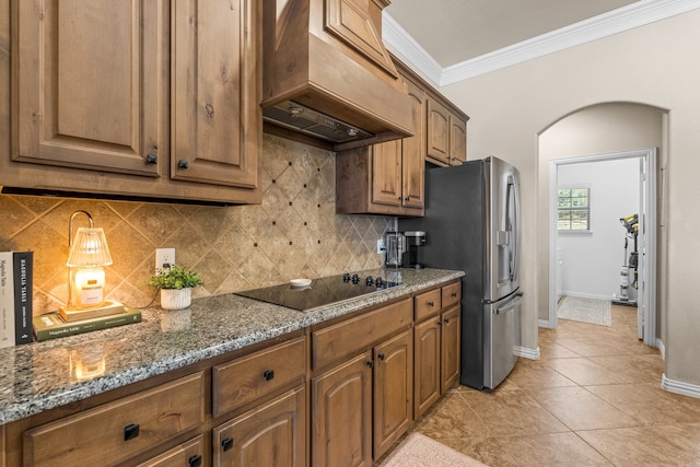 kitchen with light tile patterned floors, dark stone counters, black electric stovetop, custom exhaust hood, and decorative backsplash