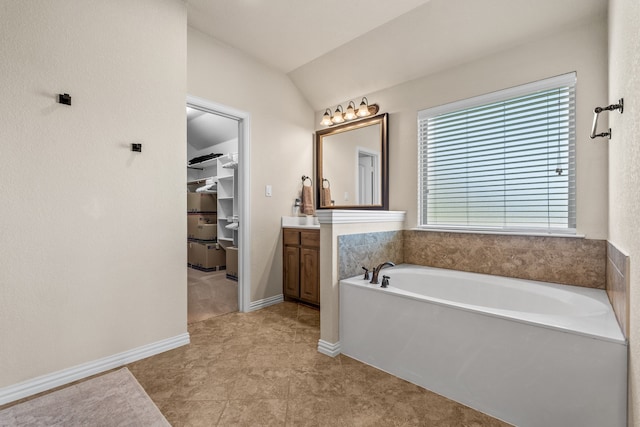 bathroom with vanity, lofted ceiling, tile patterned flooring, and a bathing tub