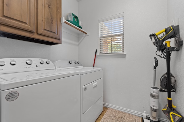 laundry area featuring light tile patterned floors, washing machine and clothes dryer, and cabinets