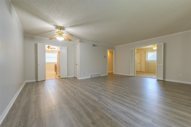 empty room featuring hardwood / wood-style flooring, a textured ceiling, crown molding, and ceiling fan