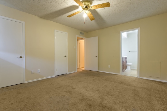 unfurnished bedroom with ensuite bathroom, light carpet, ceiling fan, and a textured ceiling