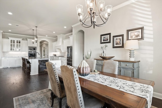 dining area with dark hardwood / wood-style floors, ornamental molding, beverage cooler, and an inviting chandelier