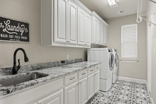 clothes washing area featuring washing machine and clothes dryer, sink, cabinets, and light tile patterned floors