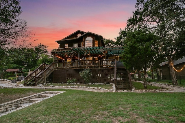 back house at dusk featuring a wooden deck and a lawn