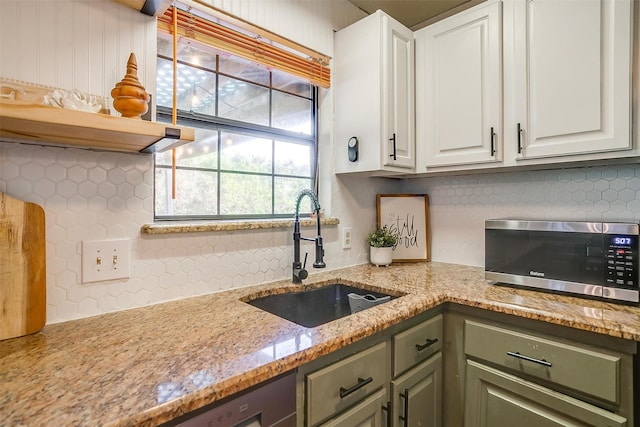 kitchen with sink, backsplash, white cabinets, and light stone counters