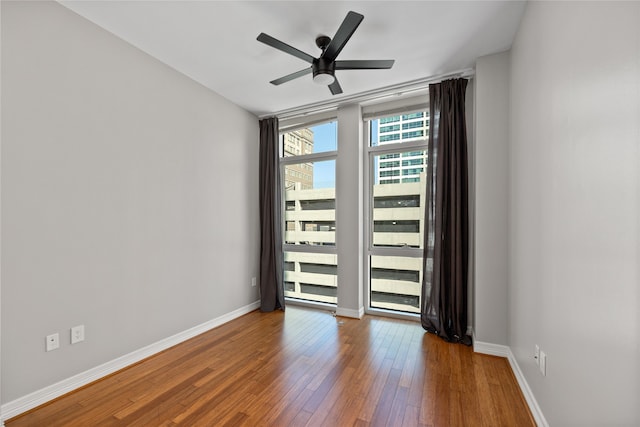 unfurnished room featuring expansive windows, wood-type flooring, and ceiling fan