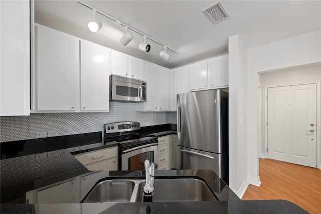 kitchen with light hardwood / wood-style flooring, stainless steel appliances, sink, backsplash, and rail lighting