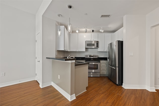 kitchen with white cabinetry, stainless steel appliances, rail lighting, decorative backsplash, and dark hardwood / wood-style floors