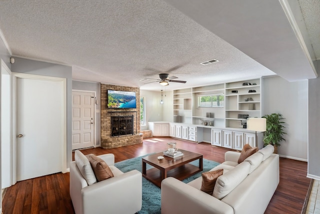 living room featuring a textured ceiling, a brick fireplace, ceiling fan, dark wood-type flooring, and brick wall