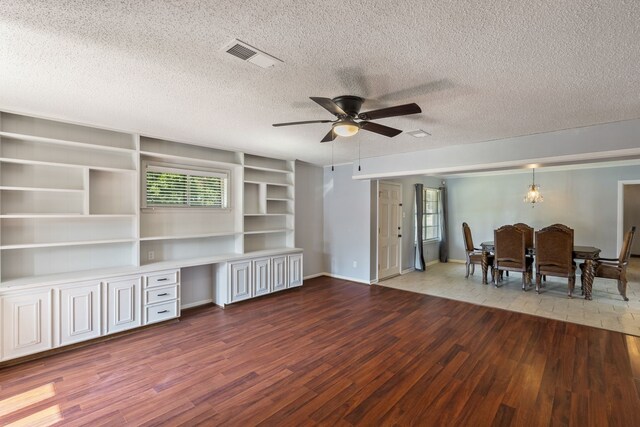 interior space featuring a textured ceiling, built in desk, ceiling fan, and hardwood / wood-style flooring