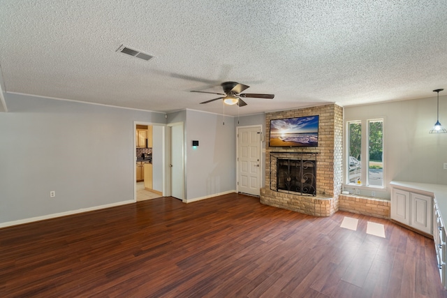 unfurnished living room featuring a textured ceiling, hardwood / wood-style flooring, and a brick fireplace