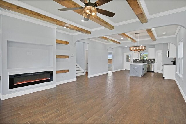 unfurnished living room featuring beam ceiling, crown molding, dark hardwood / wood-style flooring, and ceiling fan