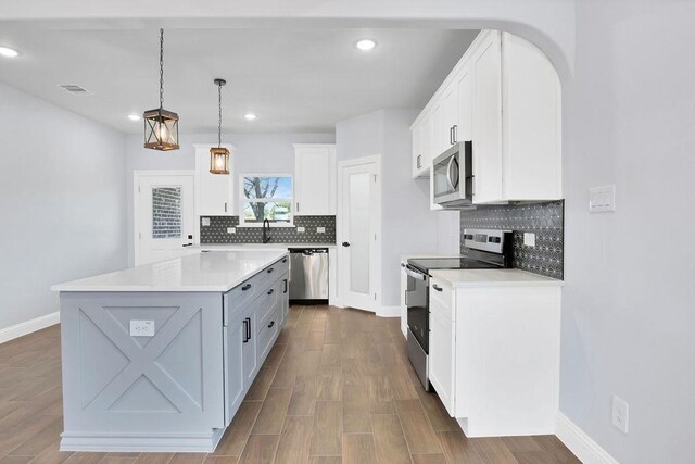 kitchen featuring white cabinets, stainless steel appliances, tasteful backsplash, and a center island