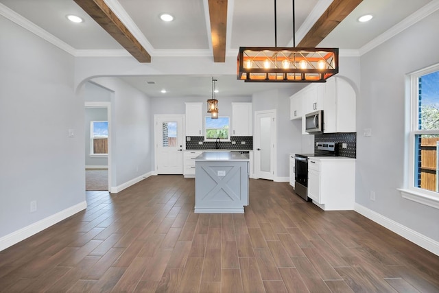 kitchen with appliances with stainless steel finishes, decorative light fixtures, beam ceiling, and tasteful backsplash