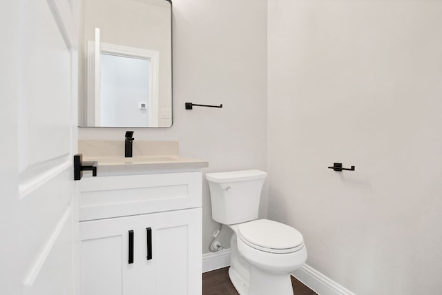 bathroom with hardwood / wood-style flooring, toilet, and vanity