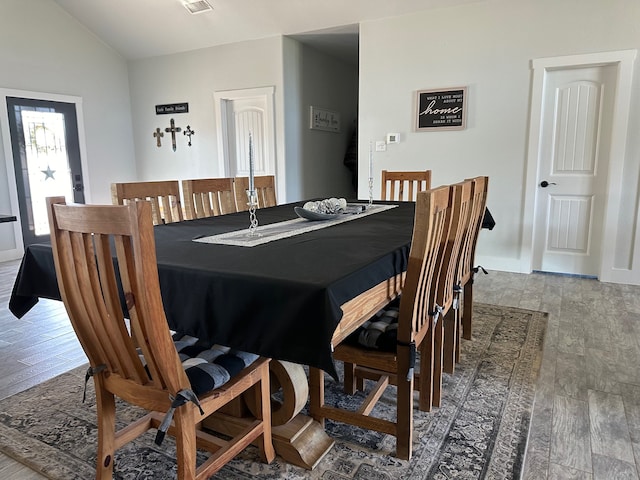 dining room featuring wood-type flooring and vaulted ceiling