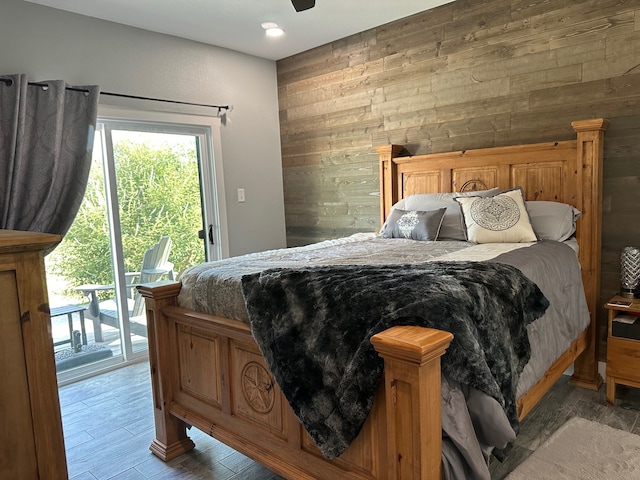 bedroom with wooden walls, hardwood / wood-style floors, and access to outside