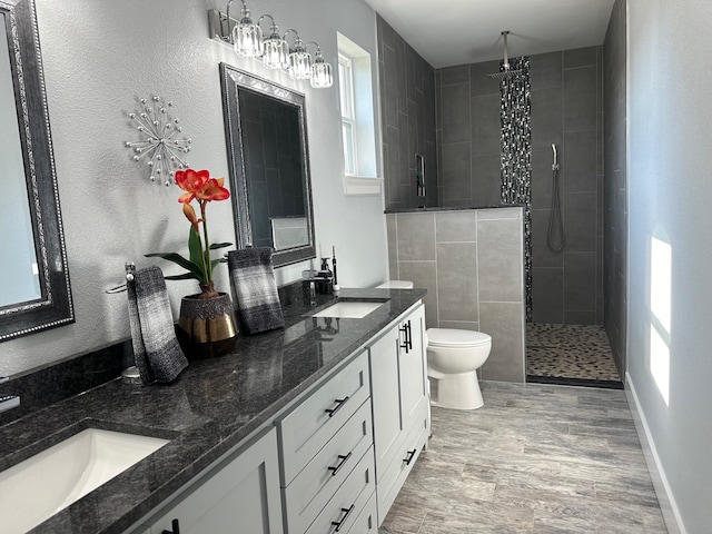 bathroom with hardwood / wood-style flooring, vanity, toilet, and tiled shower