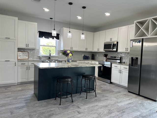 kitchen featuring white cabinets, a center island, hanging light fixtures, and appliances with stainless steel finishes