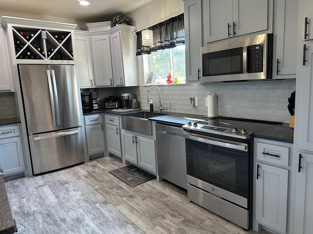 kitchen with sink, light hardwood / wood-style flooring, tasteful backsplash, white cabinetry, and stainless steel appliances