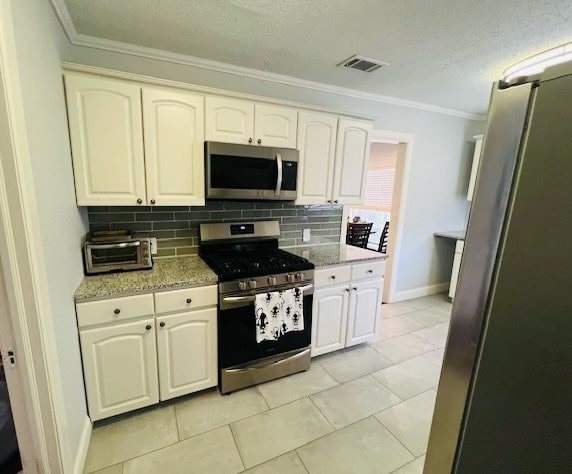 kitchen with crown molding, appliances with stainless steel finishes, tasteful backsplash, and light tile patterned floors