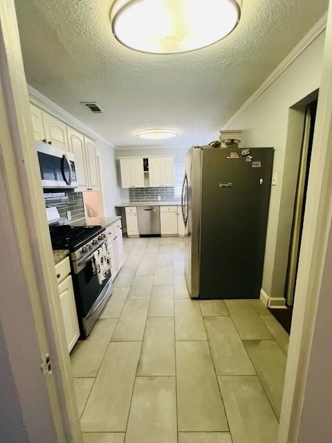 kitchen featuring appliances with stainless steel finishes, white cabinets, backsplash, light tile patterned floors, and ornamental molding