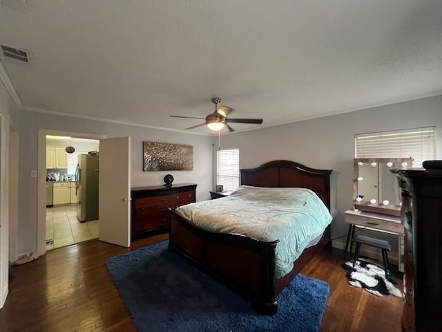 tiled bedroom with a textured ceiling, crown molding, stainless steel refrigerator, and ceiling fan