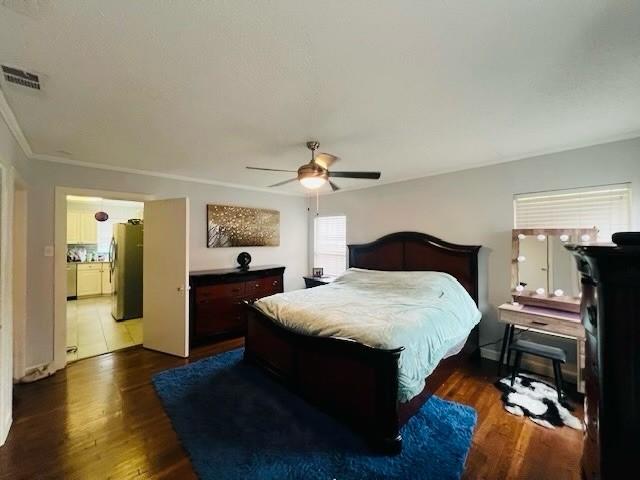 bedroom with dark hardwood / wood-style floors, stainless steel refrigerator, and ceiling fan