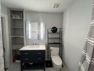 bathroom with tile patterned floors, vanity, a textured ceiling, and toilet