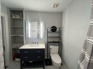 bathroom with vanity, toilet, and a textured ceiling