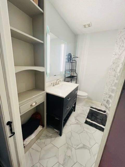 bathroom featuring vanity, toilet, tile patterned floors, and a textured ceiling