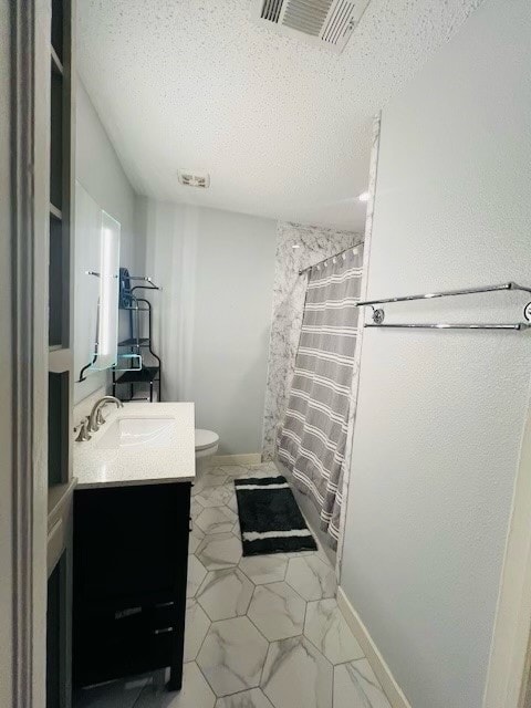 bathroom featuring vanity, tile patterned flooring, toilet, and a textured ceiling