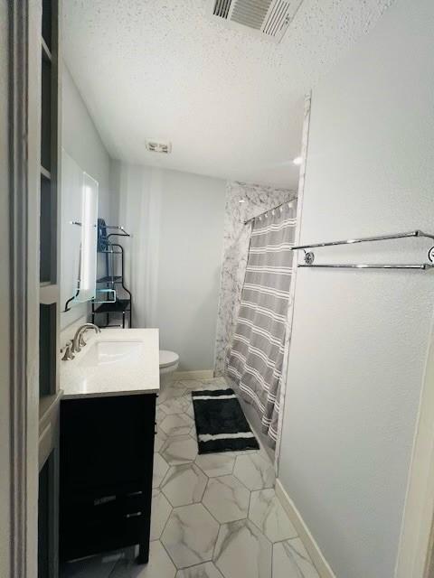 bathroom featuring vanity, curtained shower, a textured ceiling, and toilet