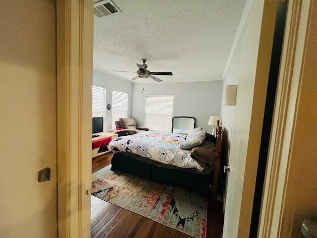 bedroom with ornamental molding, a textured ceiling, ceiling fan, and hardwood / wood-style floors