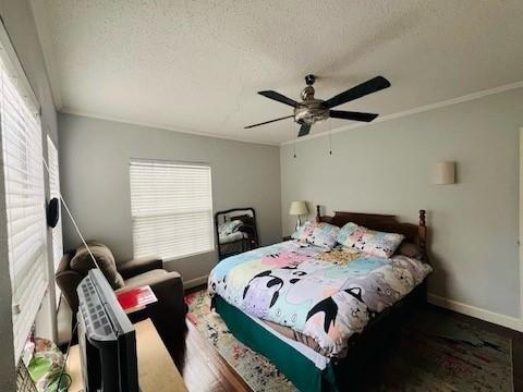 bedroom with multiple windows, crown molding, hardwood / wood-style floors, and a textured ceiling