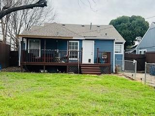 back of house with a deck and a lawn