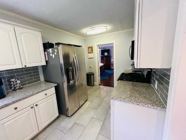 kitchen featuring appliances with stainless steel finishes, light hardwood / wood-style flooring, tasteful backsplash, white cabinets, and crown molding