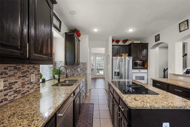 kitchen with light stone counters, stainless steel appliances, sink, and decorative backsplash