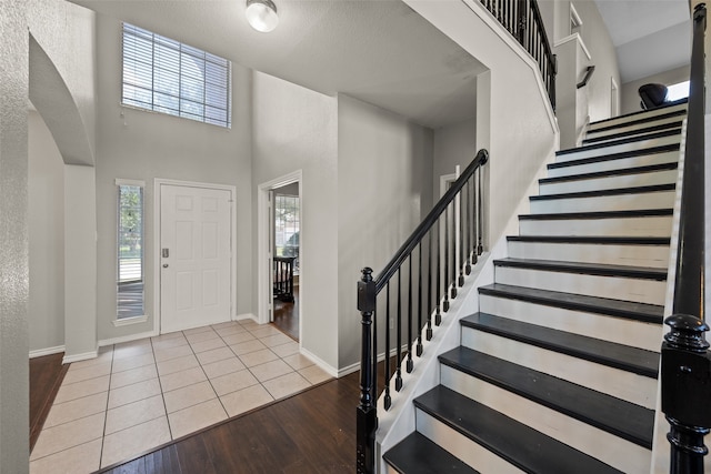 entryway featuring light wood-type flooring and a towering ceiling