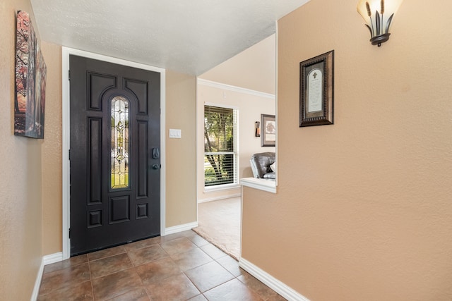 tiled foyer entrance featuring ornamental molding and a textured ceiling