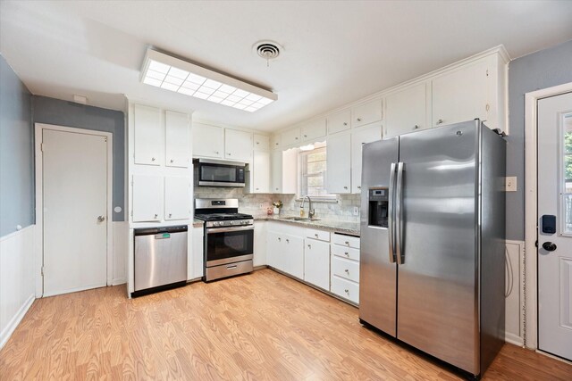 kitchen with white cabinetry, tasteful backsplash, stainless steel appliances, light hardwood / wood-style floors, and sink