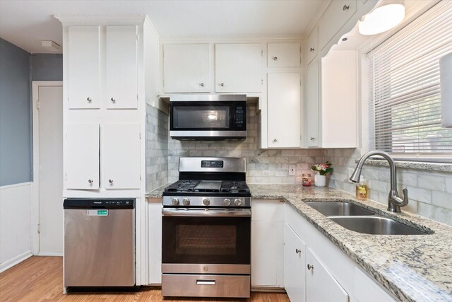 kitchen with white cabinetry, decorative backsplash, light wood-type flooring, sink, and appliances with stainless steel finishes