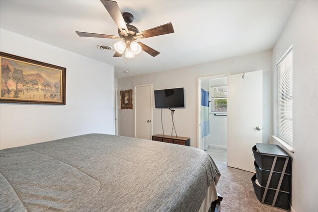 bedroom with light colored carpet, connected bathroom, and ceiling fan