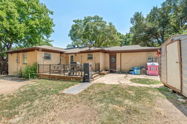 rear view of house with a shed, a wooden deck, and a lawn