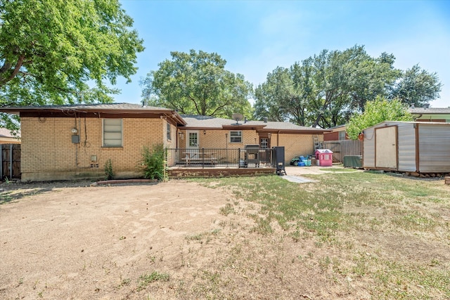 rear view of property featuring a shed and a wooden deck