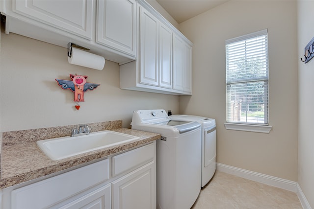 clothes washing area featuring washing machine and dryer, sink, plenty of natural light, and cabinets